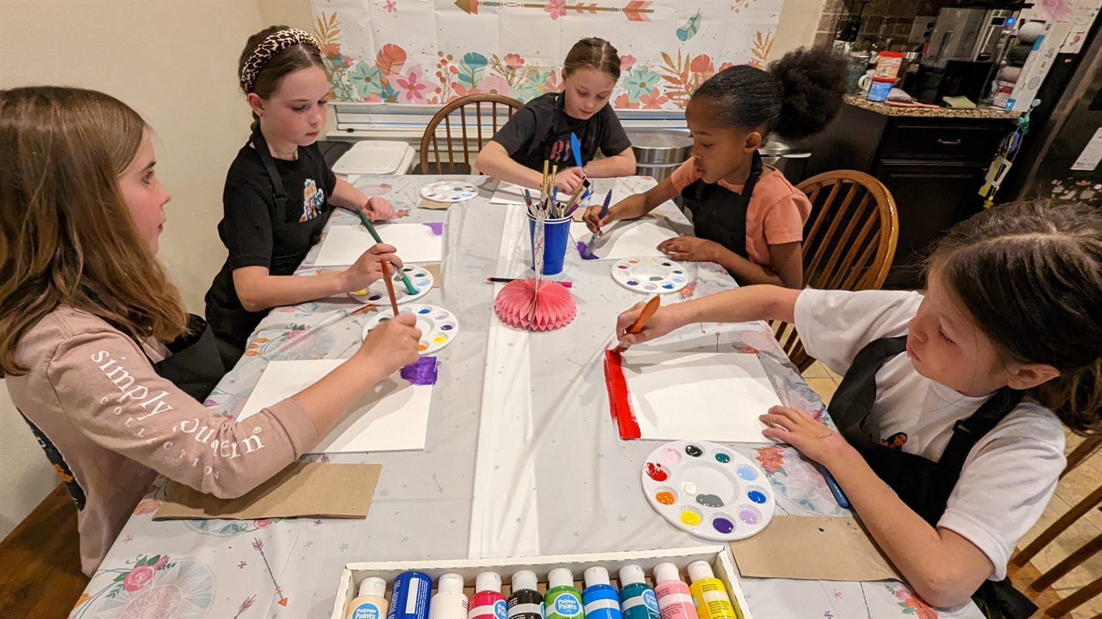 Kids painting together around a table at a SIS party