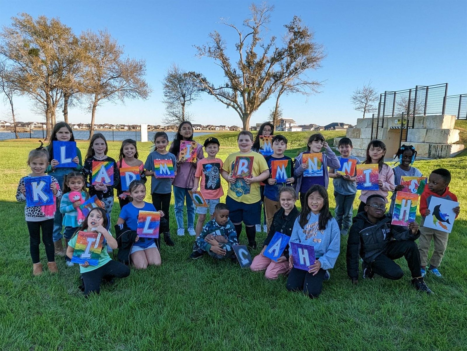 Kids showing colorful initial paintings at an outdoor SIS party