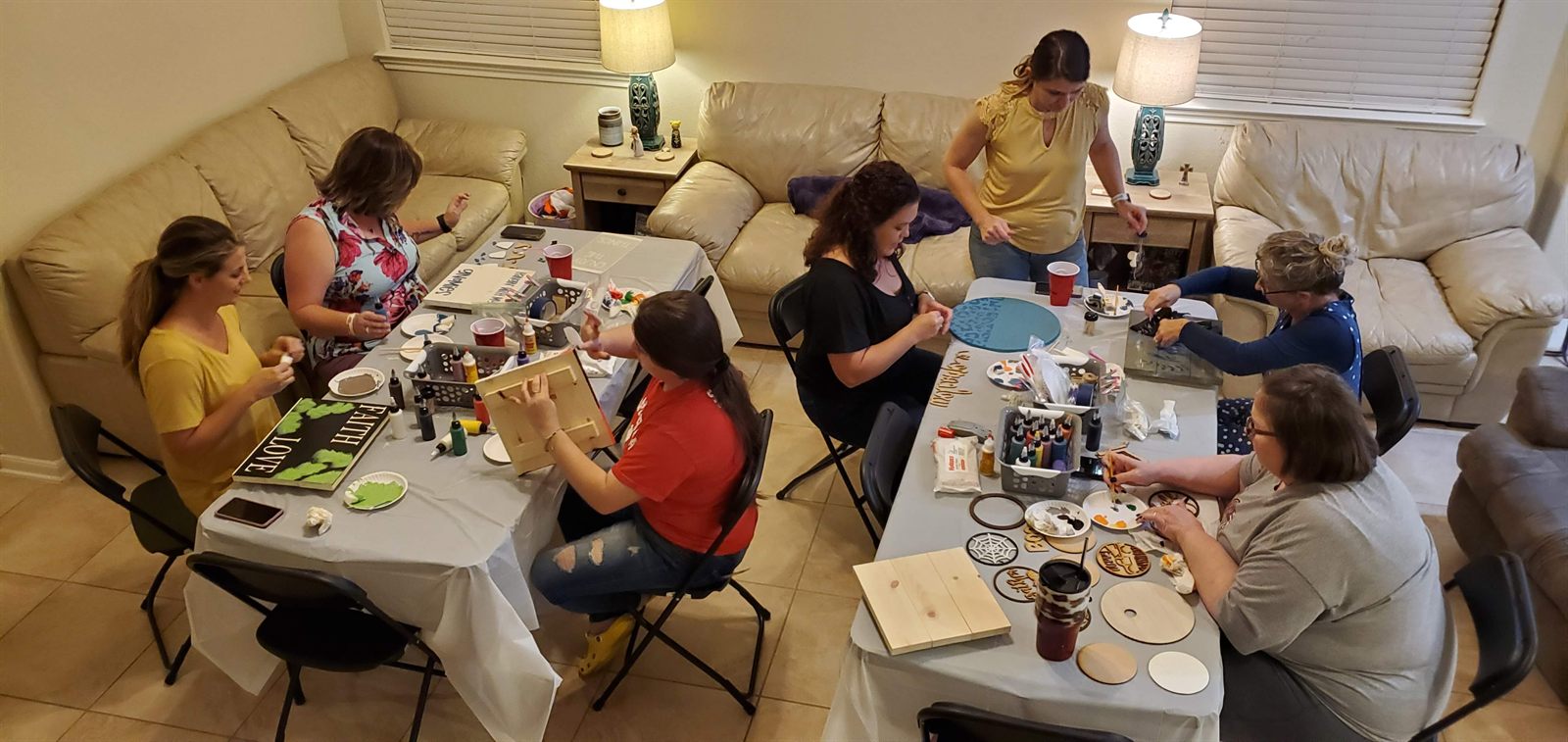 Paint party guests working on projects around tables
