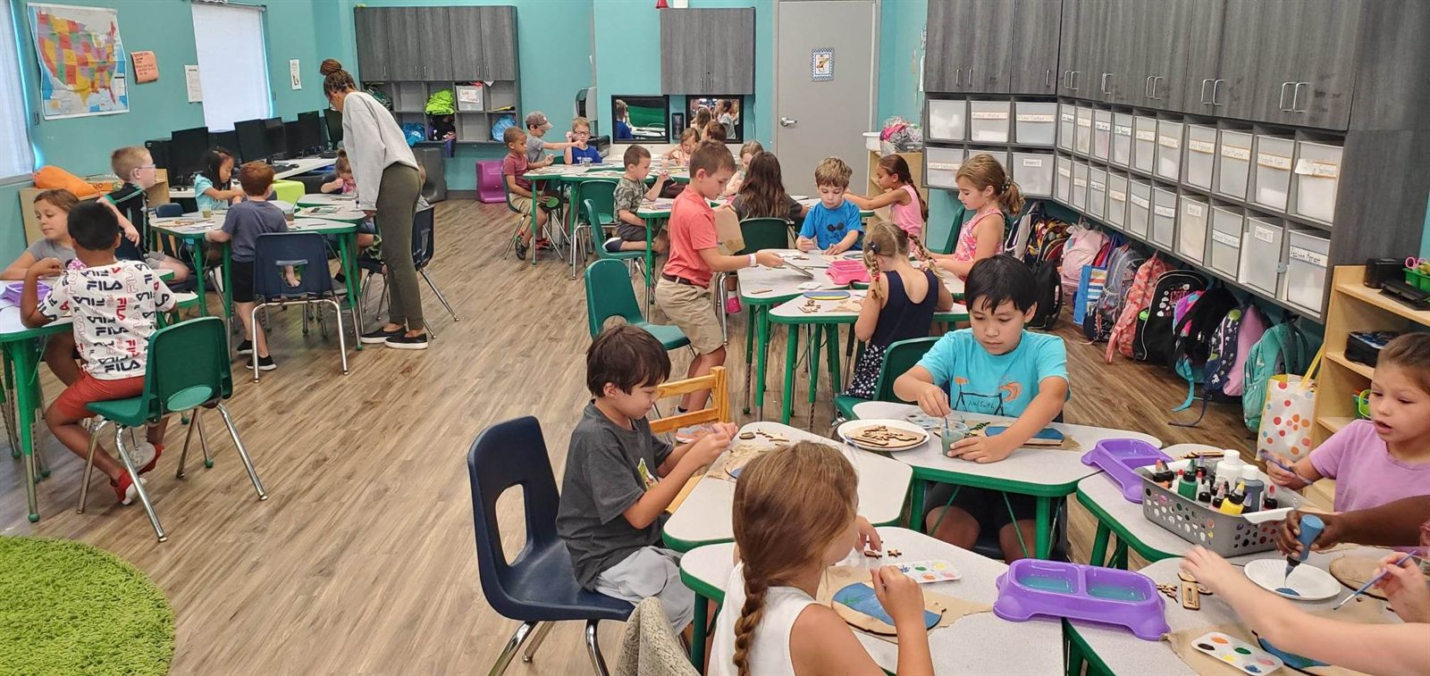 Children painting at classroom tables during a SIS school group event